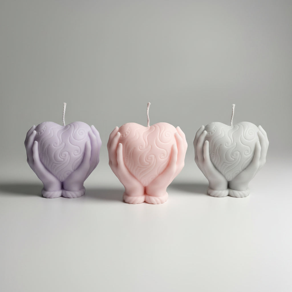 Bougie parfumée artisanale forme coeur dans les mains en rose, violet et gris