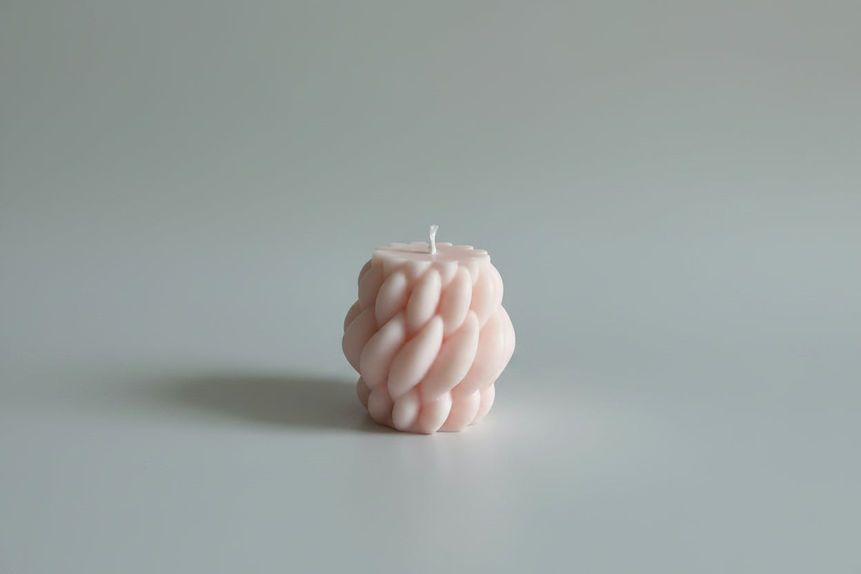 Bougie parfumée artisanale tressée rose sur fond blanc